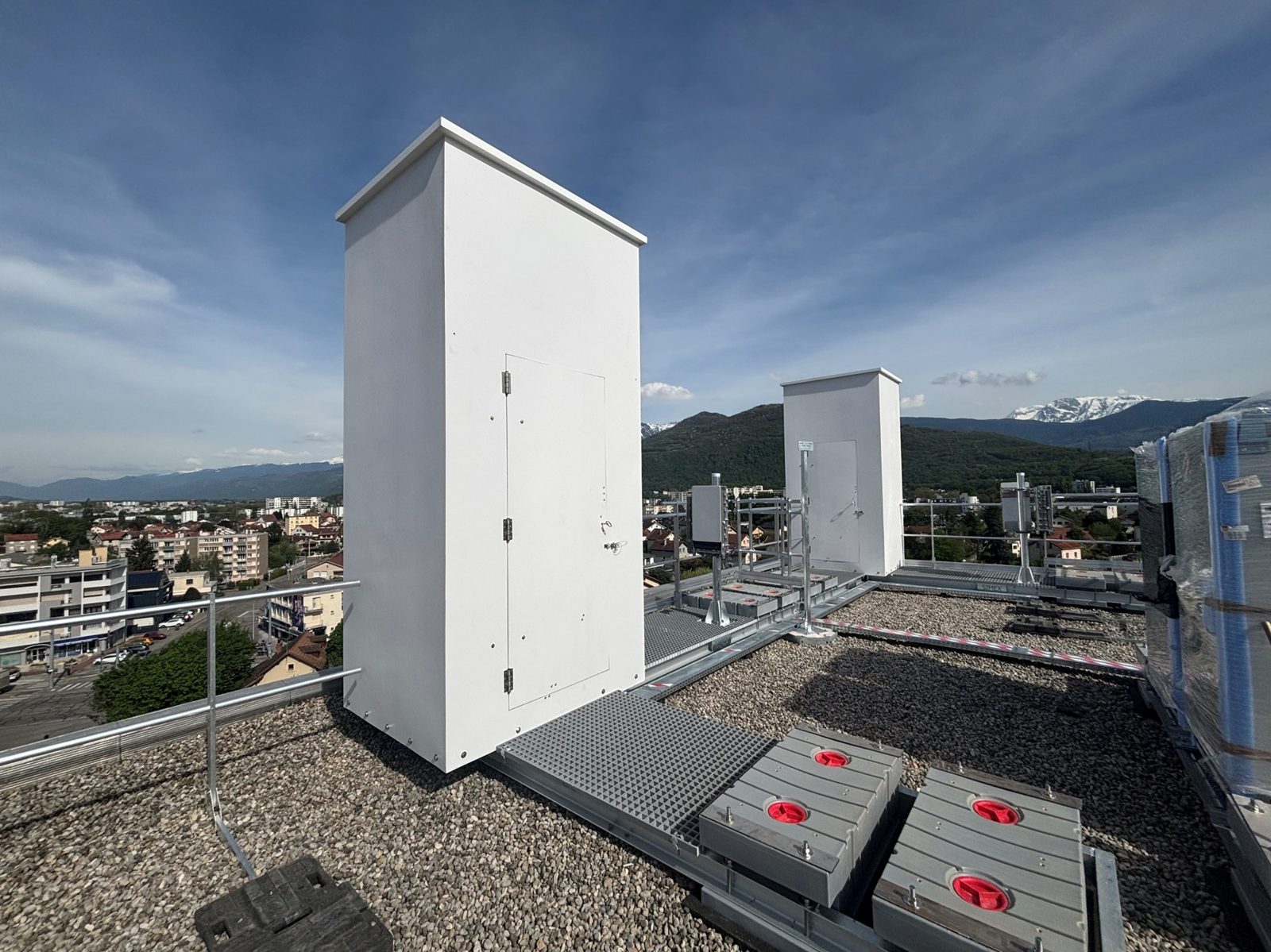 Deux fausses cheminées composites blanches sur une toiture-terrasse équipée de passerelles
