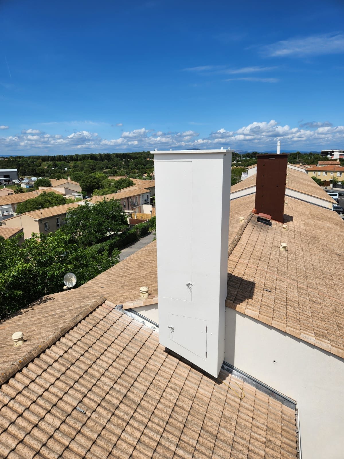 Fausse cheminée composite haute blanche avec deux portes sur une toiture en tuiles